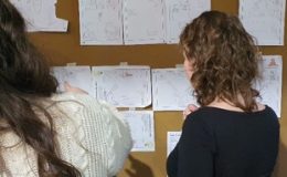 Deelnemers van een cartoontekenworkshop bekijken de cartoons van andere deelnemers.